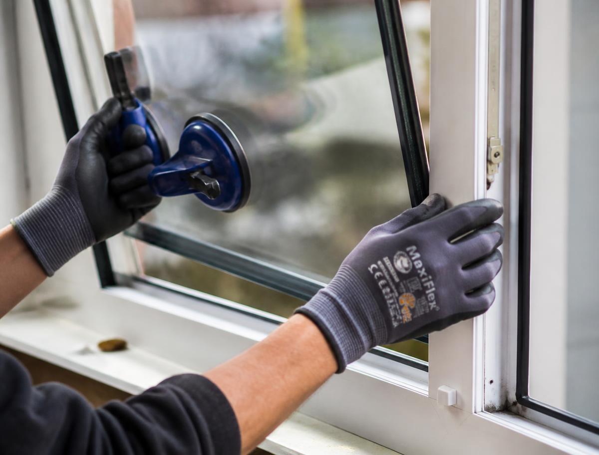 Glazier fitting a new double glazed sealed unit into a white uPVC window frame